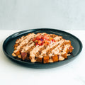 A black plate displays TexMex Potato Hash Subscription: crispy ground beef and potatoes topped with creamy sauce and fresh pico de gallo—a vibrant, gluten-free Tex-Mex dinner elegantly presented on a white background.