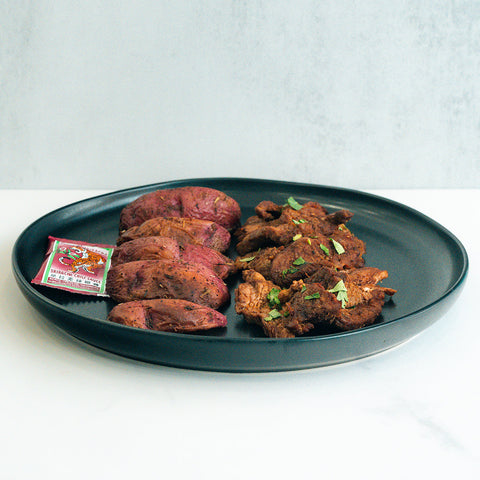 A black plate with sliced potatoes and garlic flank steak, topped with herbs and served with a side of tomato ketchup—a high-protein meal perfect for steak and potato lovers.