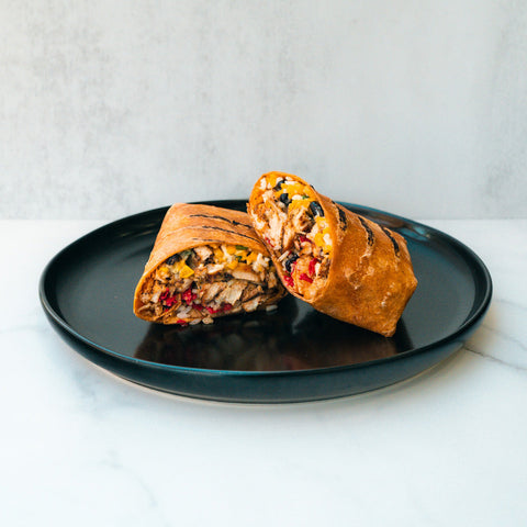The Hey Arnold Burrito Subscription, packed with high-protein chicken, rice, beans, corn, and red peppers, is sliced to show its colorful filling—ideal as a hearty post-workout meal.