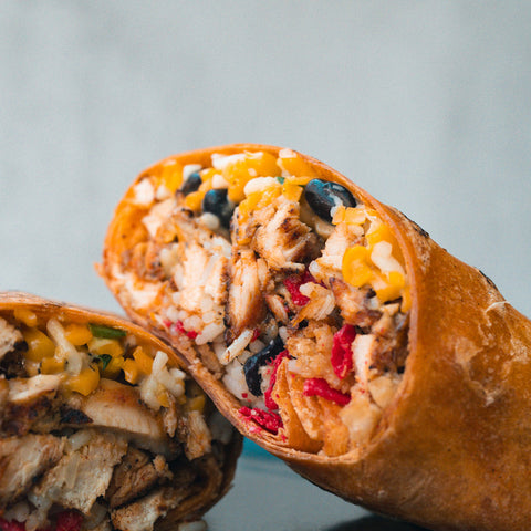A close-up of the Hey Arnold Burrito Subscription packed with grilled chicken, corn, black beans, cheese, and red bell peppers—showcasing its vibrant cross-section and making it an ideal high-protein post-workout meal.