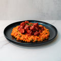 Smoky Beef Sausage and Rice features jasmine rice with peas and corn, topped with smoky beef sausage chunks and stewed meat on a black plate—a comfort meal perfect for any time.