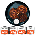 Cinnamon Roll Pancakes: three swirled pancakes on a black plate with sugar-free syrup and cream. Nutrition—485 calories, 28g protein, 64g carbs, 13g fat.